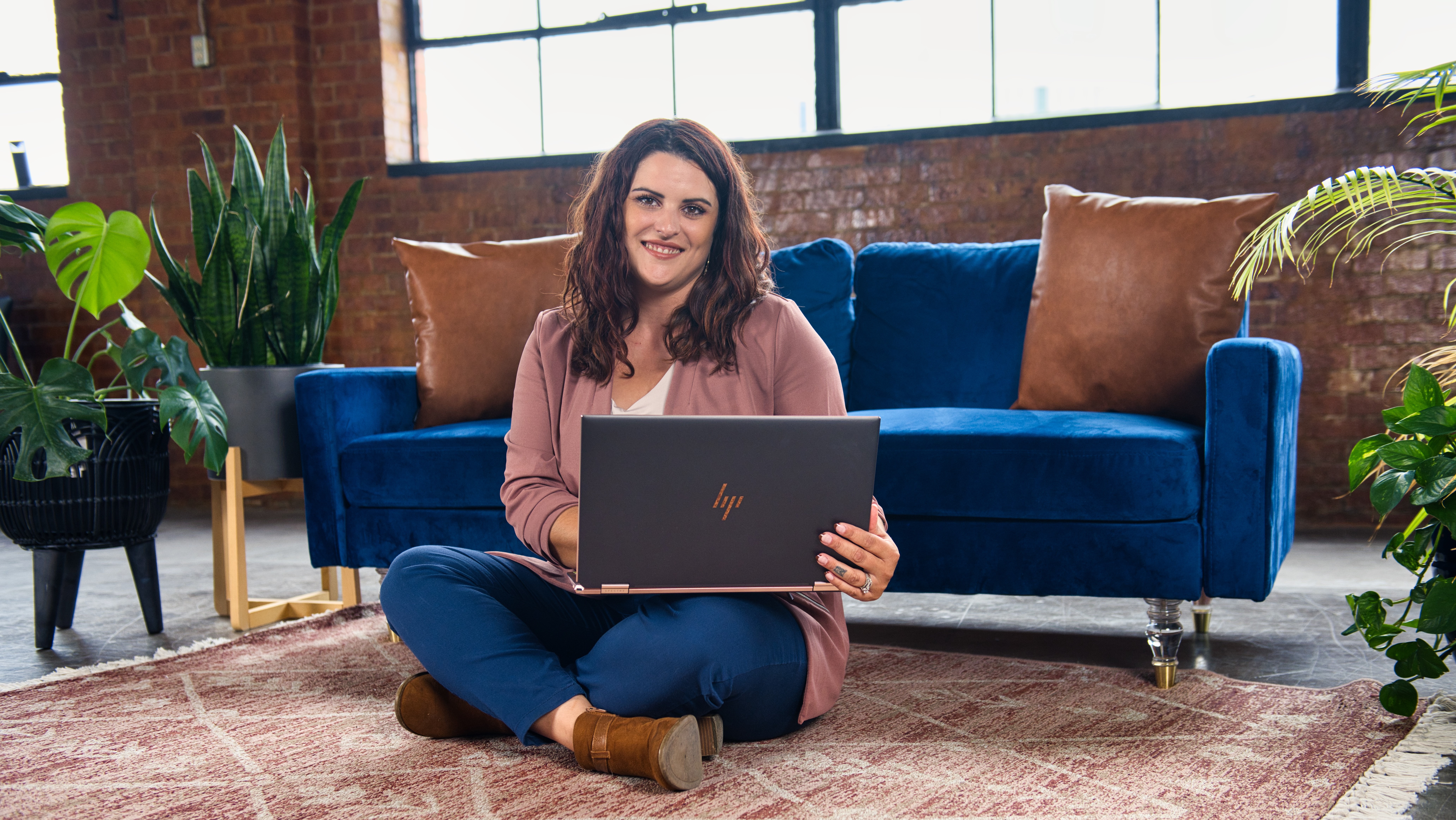 happy-woman-sitting-on-floor-on-laptop-smiling-at-camera