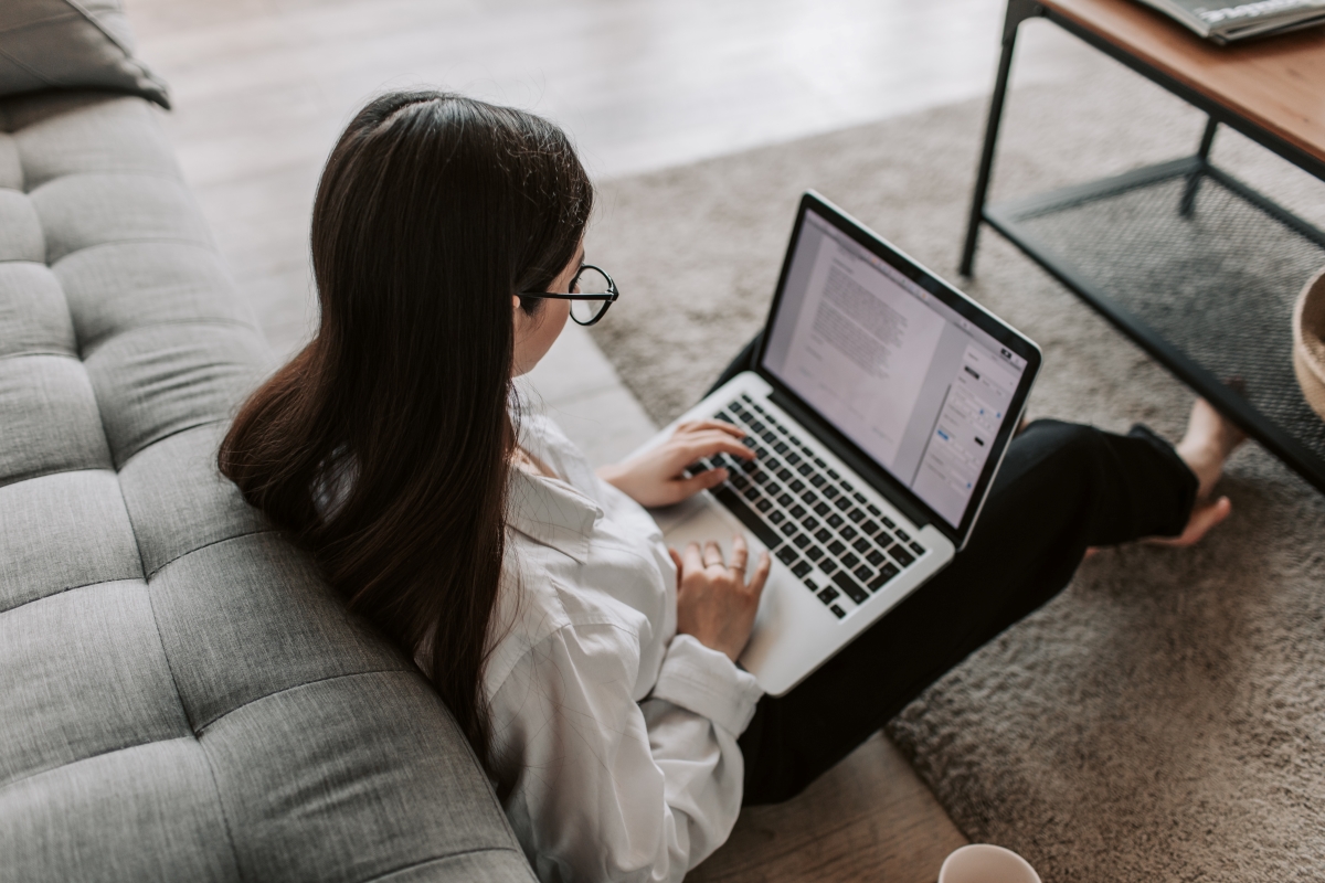 A woman sitting on the floor with a laptop, working on a document, representing the process of setting up new systems for efficiency.