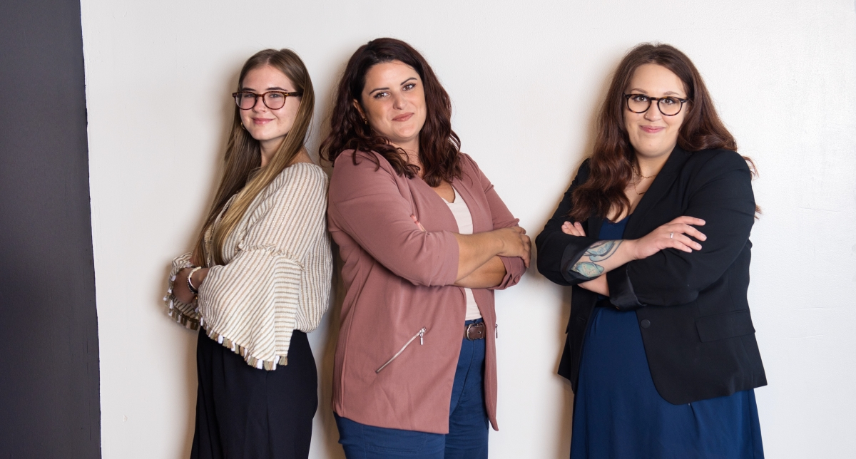 Three confident women standing with arms crossed, representing a skilled and professional team for hiring a virtual assistant.