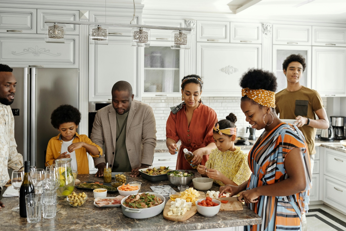 A family gathered in the kitchen preparing a meal together, symbolizing holiday planning and togetherness.