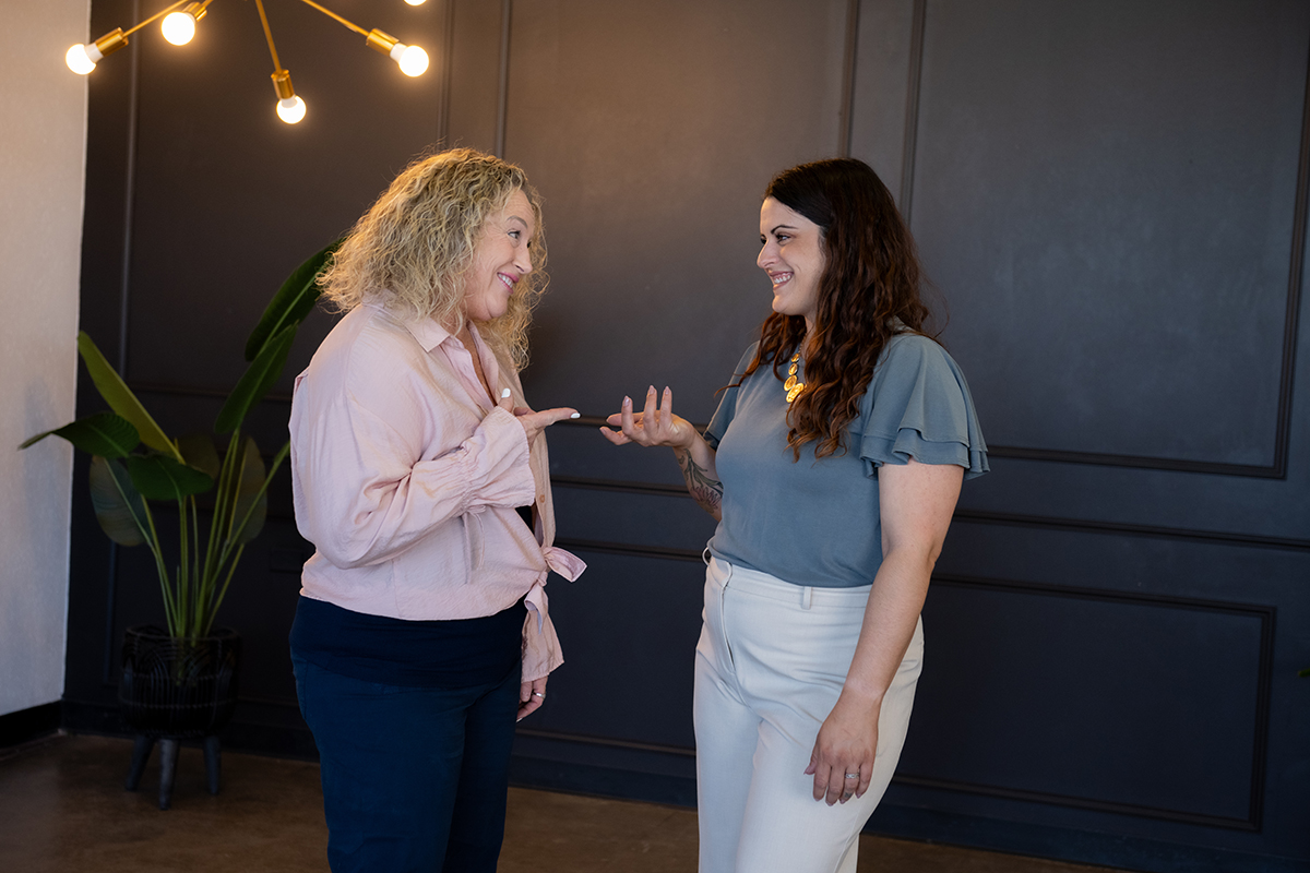 Two women engaging in a friendly discussion, illustrating the supportive relationship between a virtual assistant and her client.