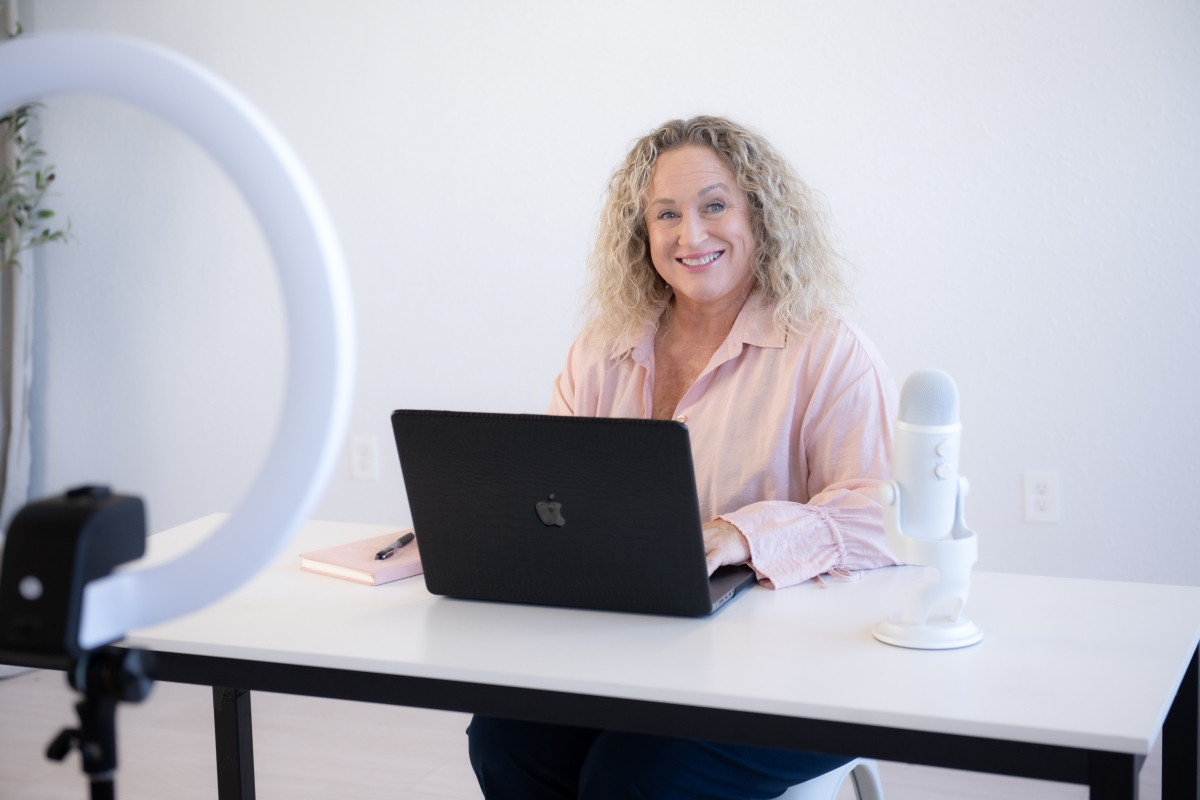 Woman smiling at laptop during video recording session about SOP creation and overcoming operational bottlenecks.