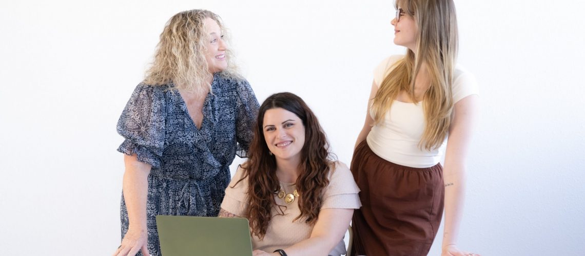 three-business-women-talking-and-smiling-behind-desk