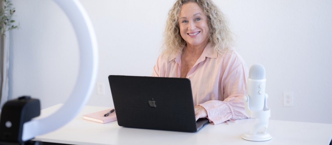 Woman smiling at laptop during video recording session about SOP creation and overcoming operational bottlenecks.