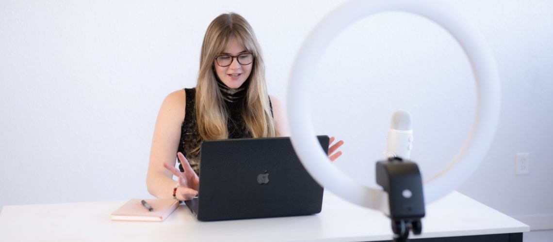 Woman hosting a virtual meeting with a laptop, ring light, and microphone — showcasing the benefits of hiring a virtual assistant for business efficiency.