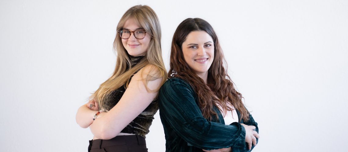 two-business-women-back-to-back-smiling