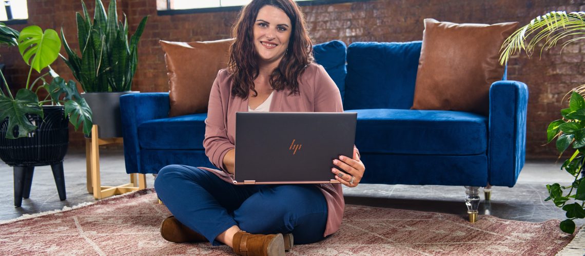 business-woman-sitting-on-floor-smiling-and-on-laptop