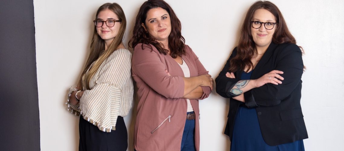 Three confident women standing with arms crossed, representing a skilled and professional team for hiring a virtual assistant.