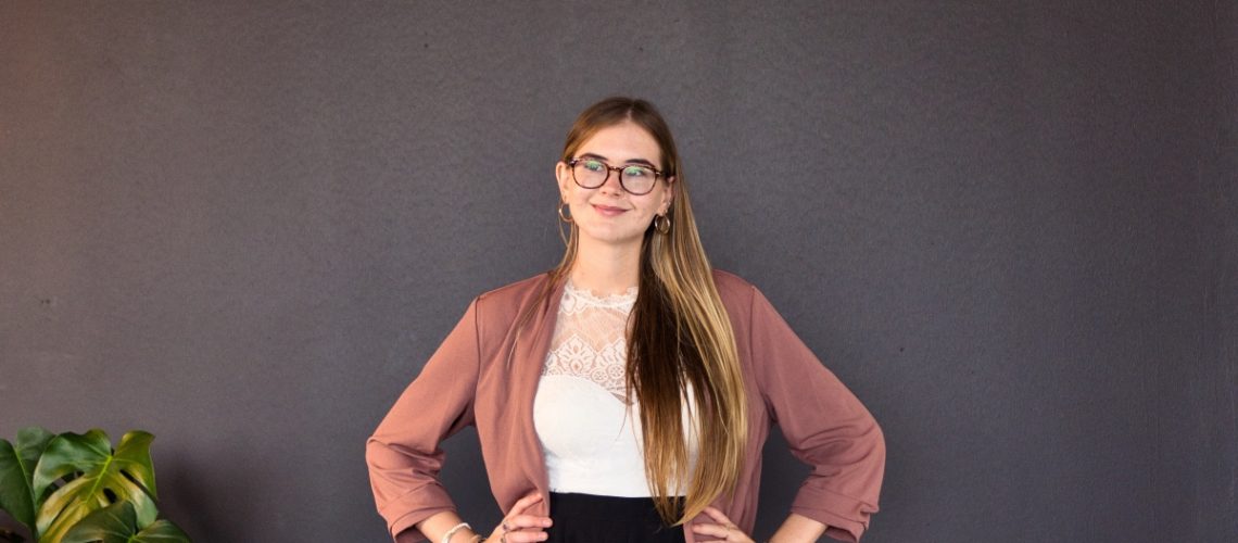 A confident woman in professional attire standing with hands on her hips, representing self-reflection and growth during the holiday season.