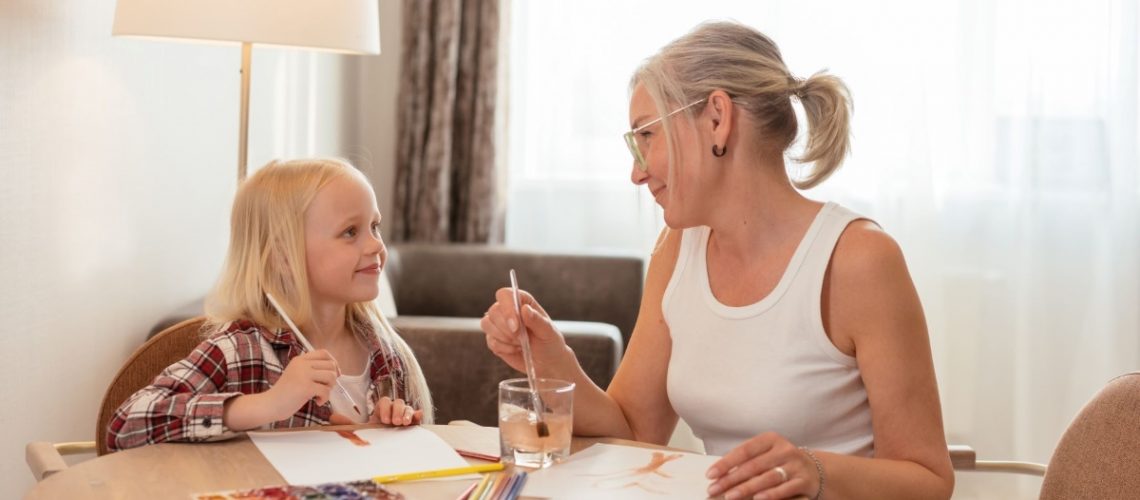 A grandmother and granddaughter painting together at a table, enjoying quality time during the holiday season.