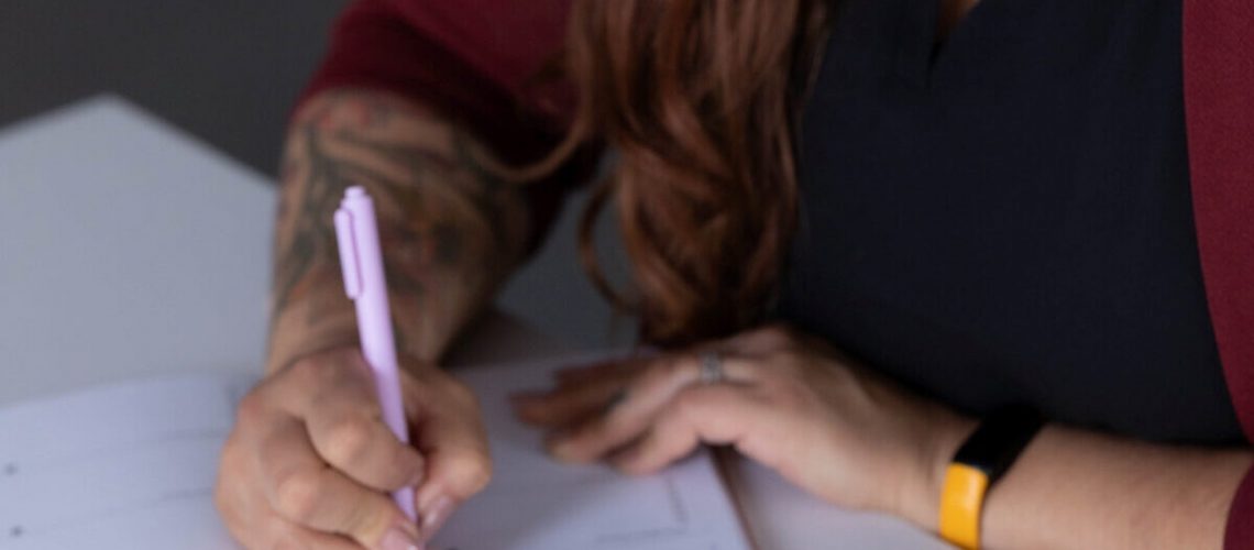 A professional woman writing in a planner, documenting SOP onboarding steps.