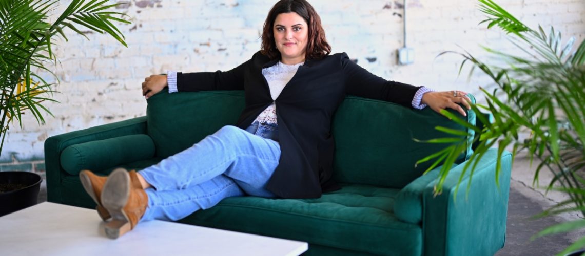 A confident woman sitting on a stylish green couch, exuding expertise and authority.