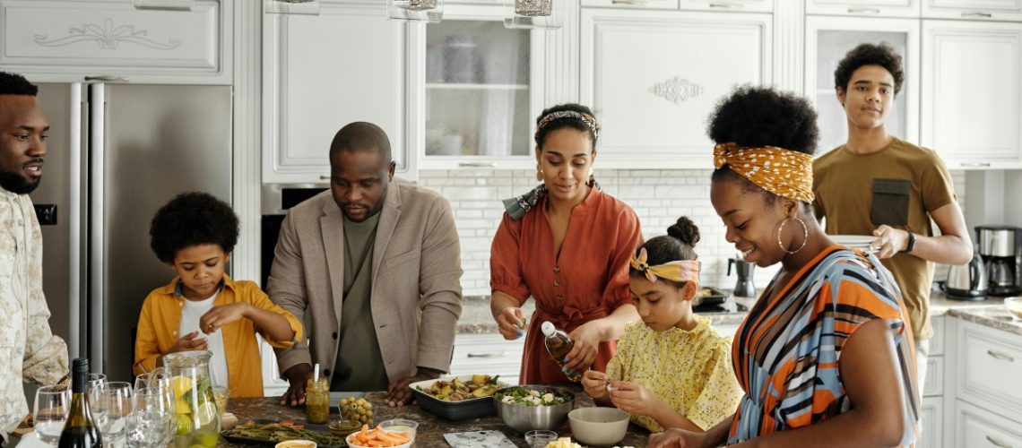 A family gathered in the kitchen preparing a meal together, symbolizing holiday planning and togetherness.
