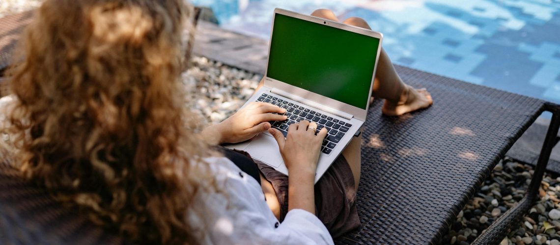 woman-working-on-laptop-by-pool-during-summer